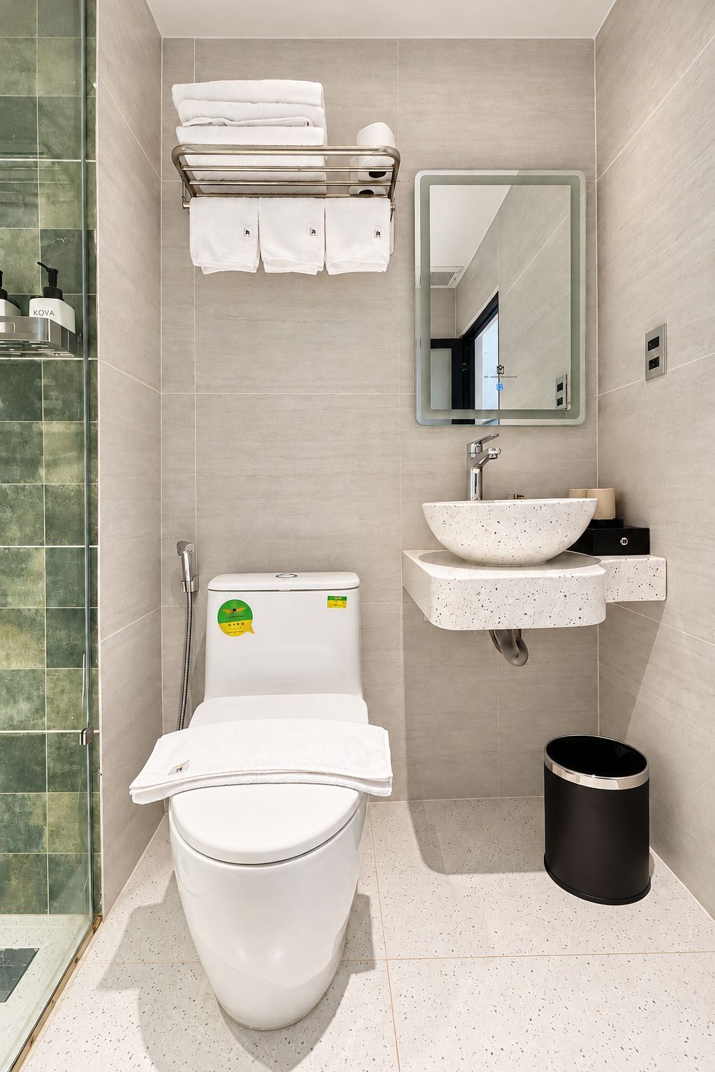 Et moderne badeværelse med toilet, håndvask og bruser.