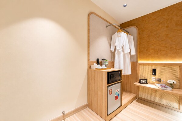 A modern bathroom with a wooden vanity, a towel rack with robes, a microwave, and a small refrigerator. - KOVA Hotel - Bui Vien Central (Ho Chi Minh City)
