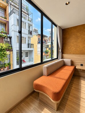 A modern room with a large window, a wooden floor, and a bench. - KOVA Hotel - Bui Vien Central (Ho Chi Minh City)