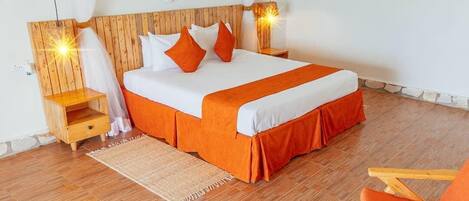 A bedroom with a wooden headboard, a bed with white and orange bedding, a nightstand, a chair, and a rug.