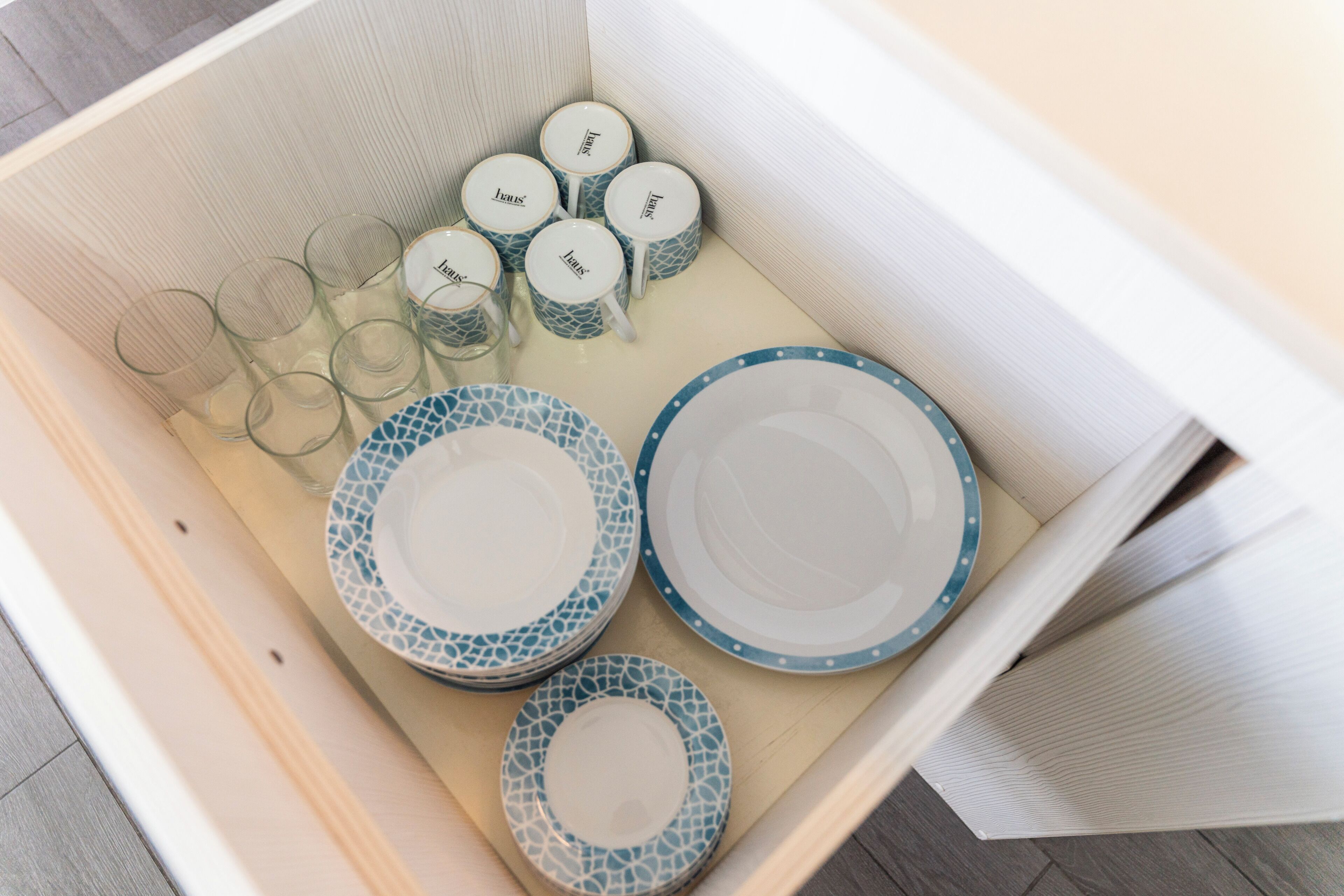 A drawer with plates, glasses, and mugs.