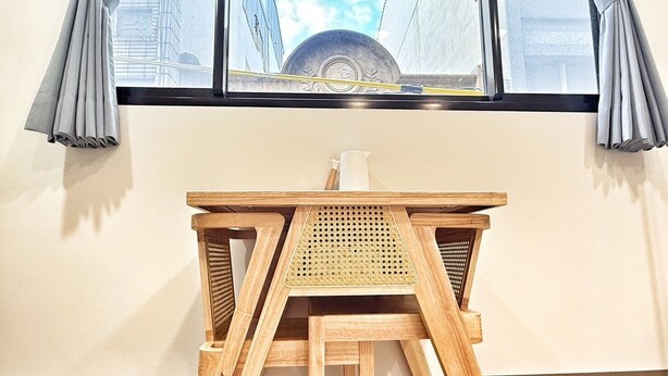 A wooden desk with a woven chair in a room with a window. - Linshouse (Tainan)
