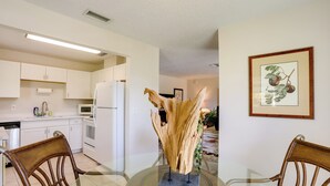 Una cocina moderna con armarios blancos, un refrigerador blanco y una mesa de comedor con sillas.