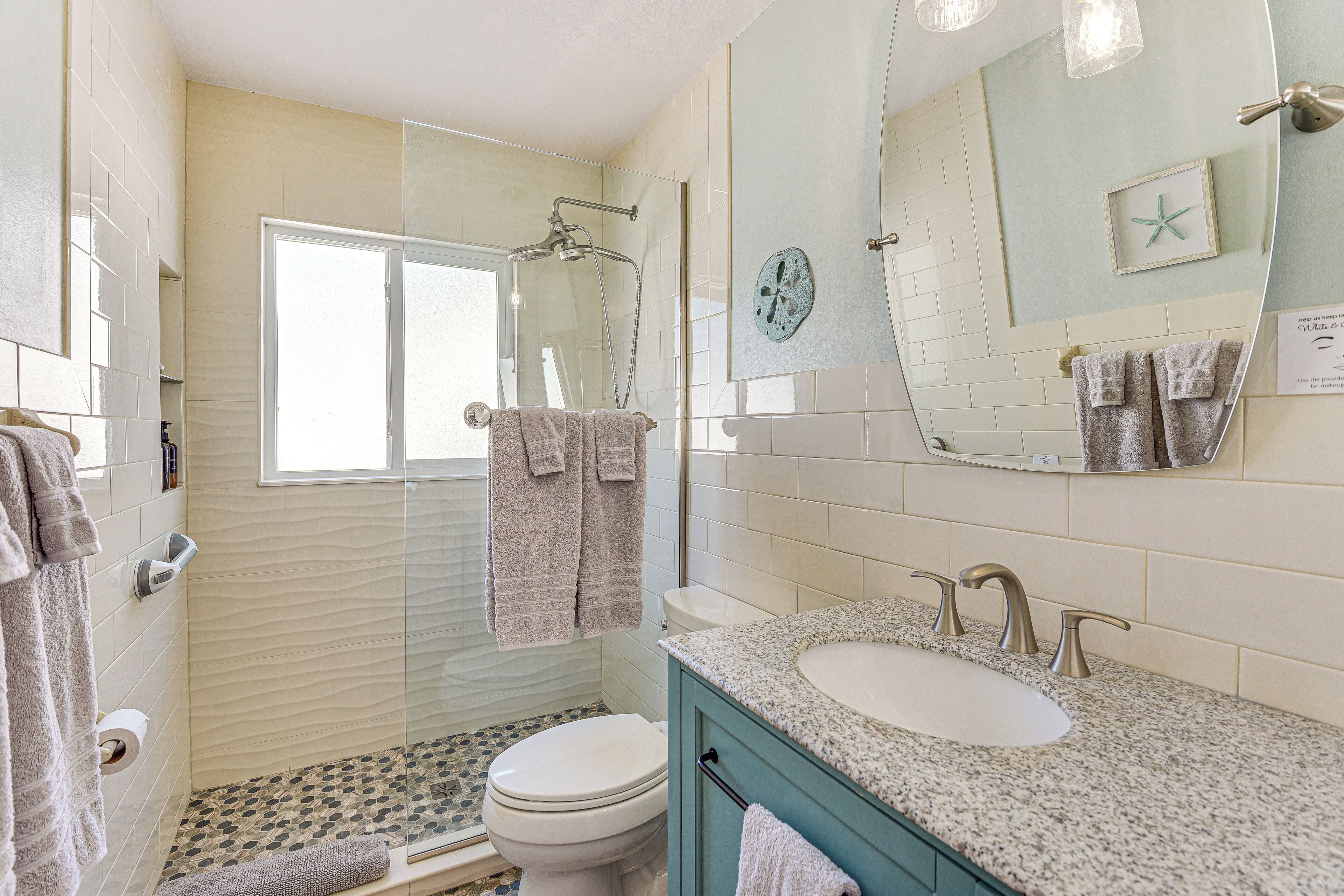 A bathroom with a shower, toilet, sink, and towel rack.