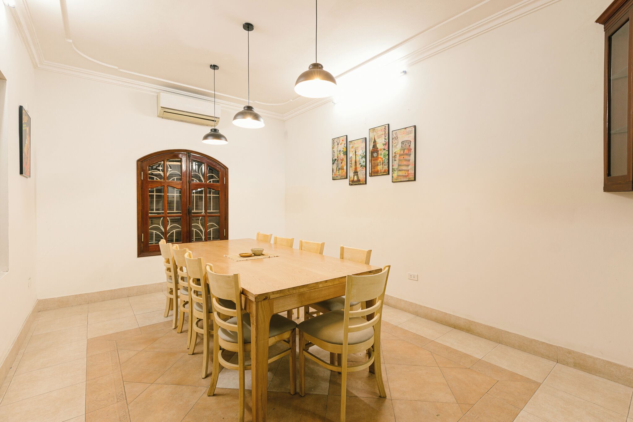 A dining area with a wooden table and chairs, a large window with decorative glass, and wall-mounted artwork.