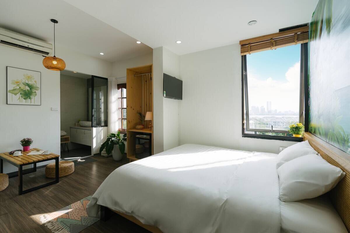 Een moderne slaapkamer met een groot bed, een aan de muur bevestigde televisie en een raam met uitzicht over de stad.