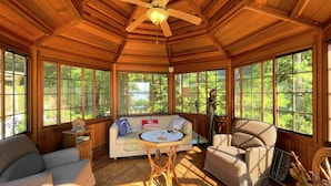 A sunroom with wooden beams, large windows, a glass table, and a sofa with pillows. - Discover Tranquility and Adventure at Head Lake (Kirkfield)