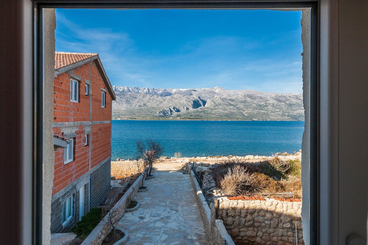 Un sentier de pierres qui mène à un point de vue sur la côte, avec une montagne en arrière-plan.