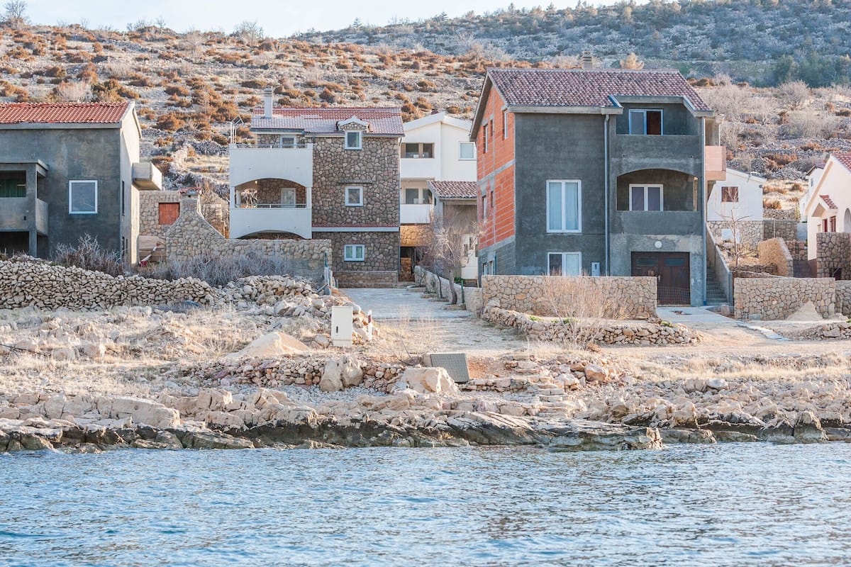 Un village côtier aux bâtiments en pierre, avec un rivage rocheux et une vue dégagée sur la mer.