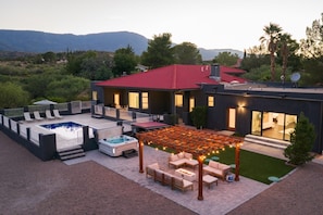 Una casa moderna con piscina, mobiliario de exterior y un patio cubierto.