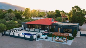 A modern house with a swimming pool, outdoor seating, and a pergola.