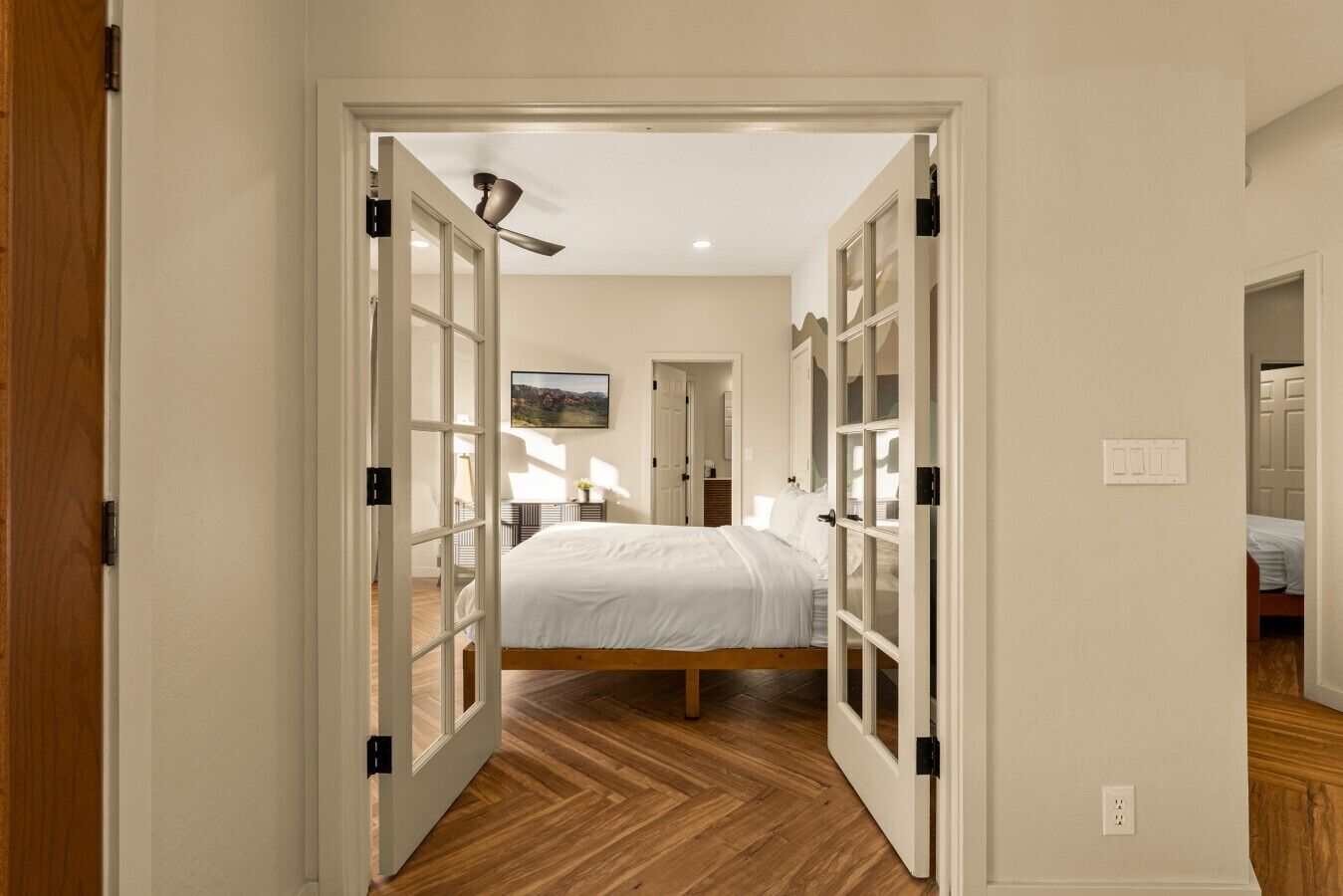 A bedroom with a bed, wooden flooring, and a ceiling fan.