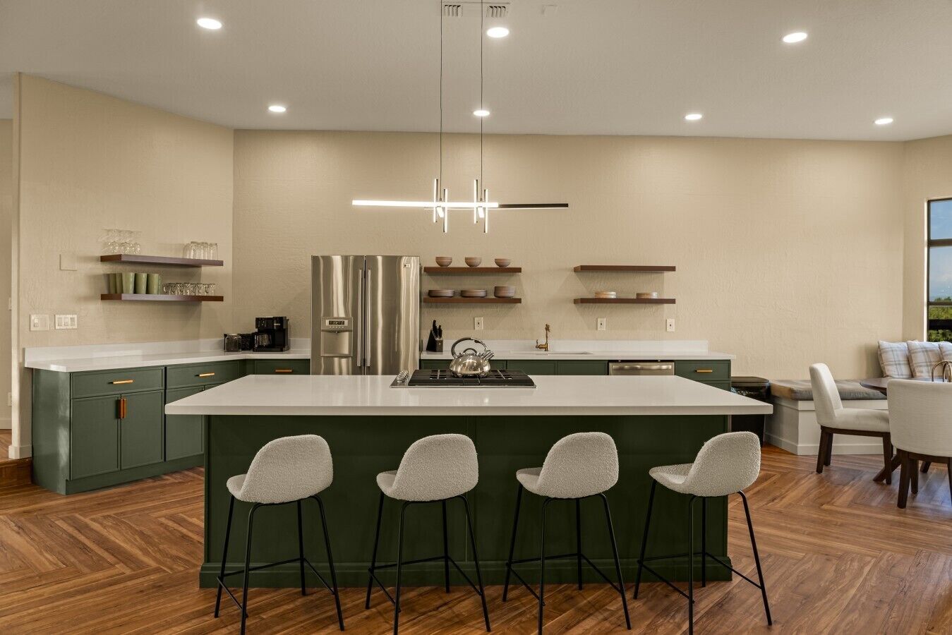 Una cocina moderna con una isla central, taburetes de bar y un comedor con vistas.