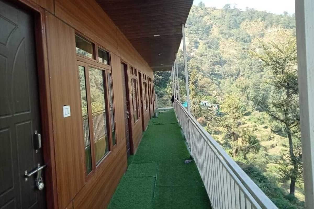 A wooden building with a balcony overlooking a hilly landscape.
