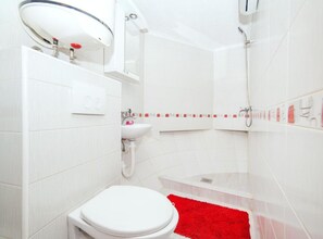 Un baño moderno con inodoro blanco, lavabo y ducha.