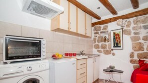 A compact kitchen with a washing machine, a microwave, and a small dining area with a table and chairs. - Cozy Stay in Kotors Old Town (Kotor)