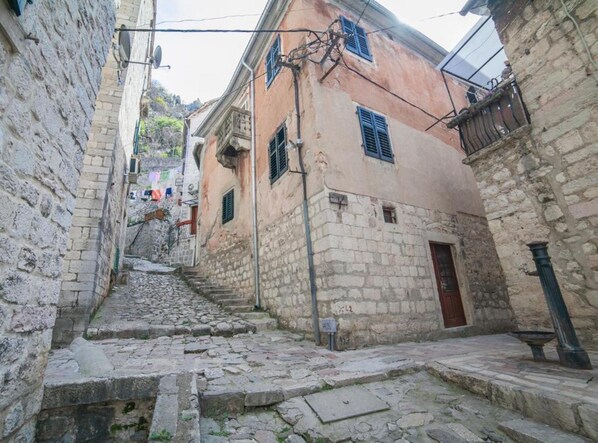 Una estrecha calle empedrada flanqueada por edificios históricos de piedra, que muestran signos de antigüedad y arquitectura tradicional.
