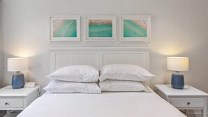 A hotel room with a bed, white nightstands, and three framed artworks above the bed. - Bright & Spacious 1-Bed in Vibrant Sydney (Sydney)
