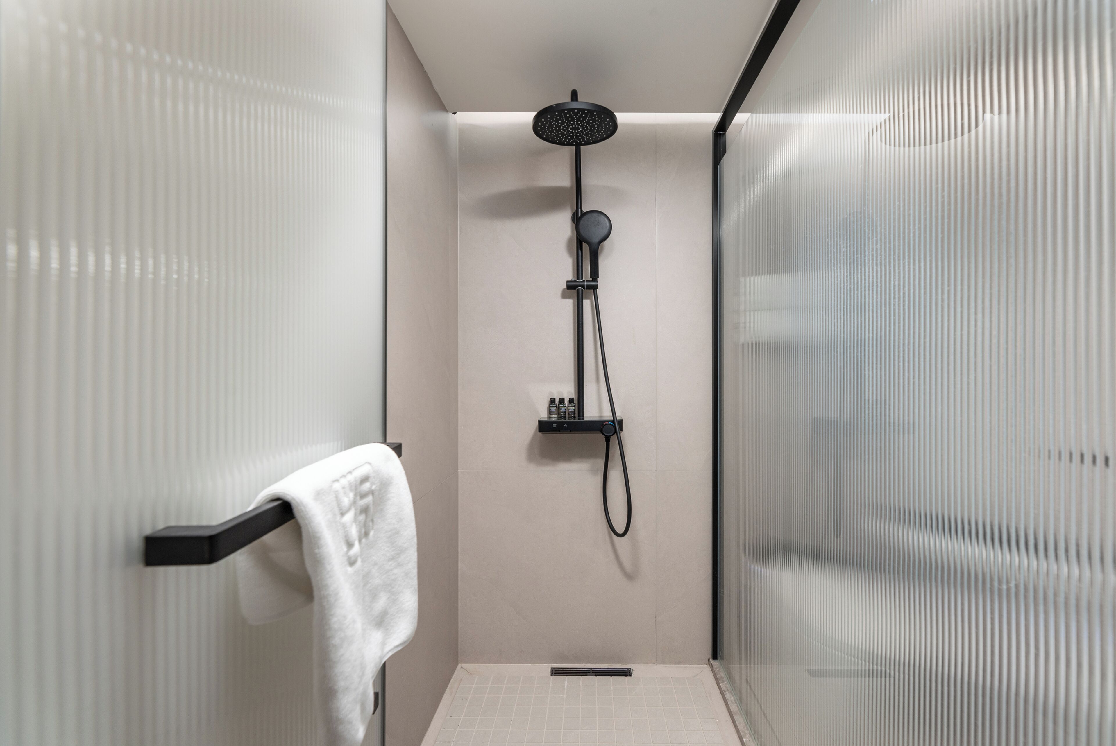 Une douche moderne dotée d’un pommeau de douche à main et d’un flexible de douche.