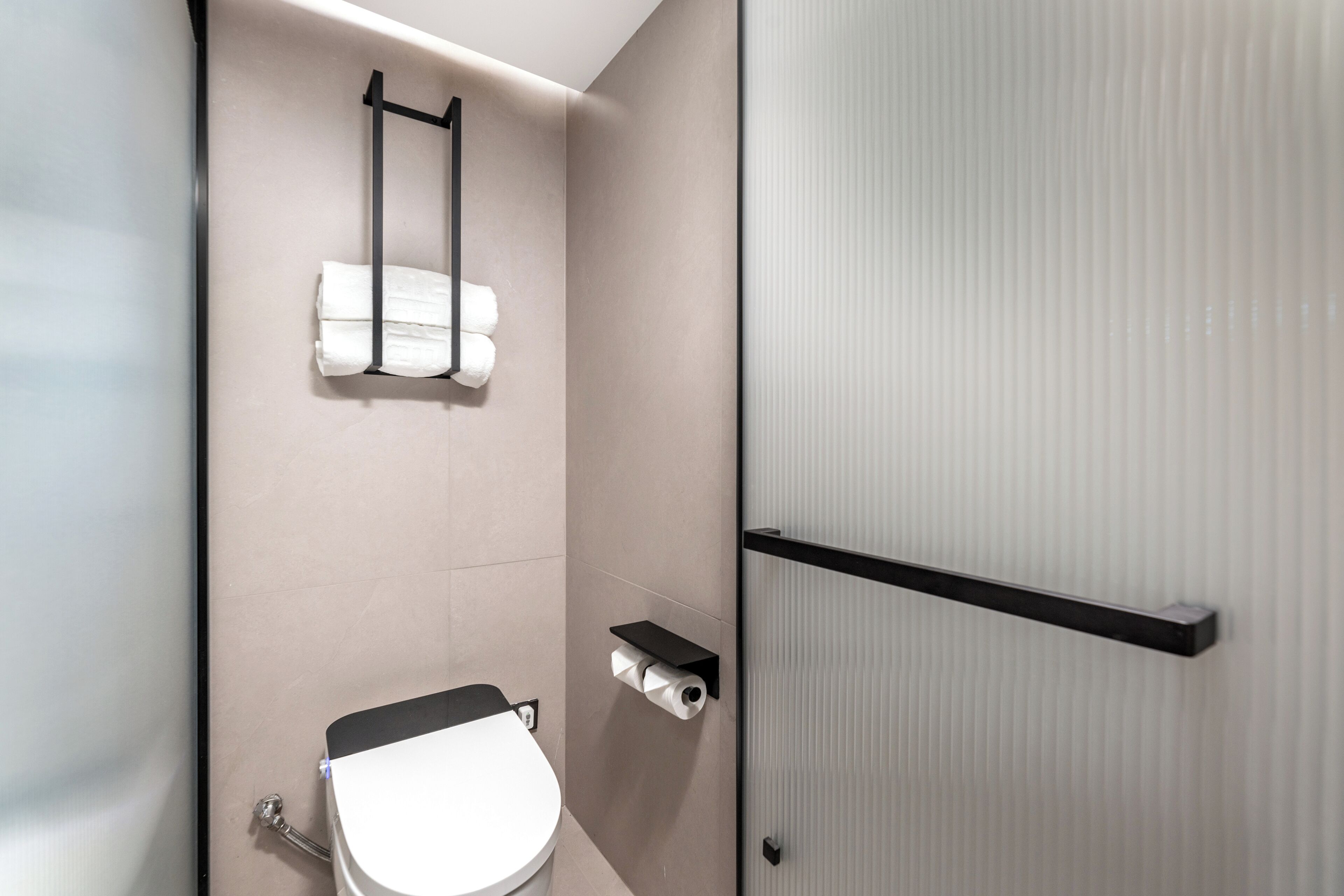 Ein modernes Badezimmer mit Toilette, Handtuchhalter und Toilettenpapierhalter.