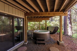 Un jacuzzi bajo una pérgola de madera con vistas a un área boscosa.