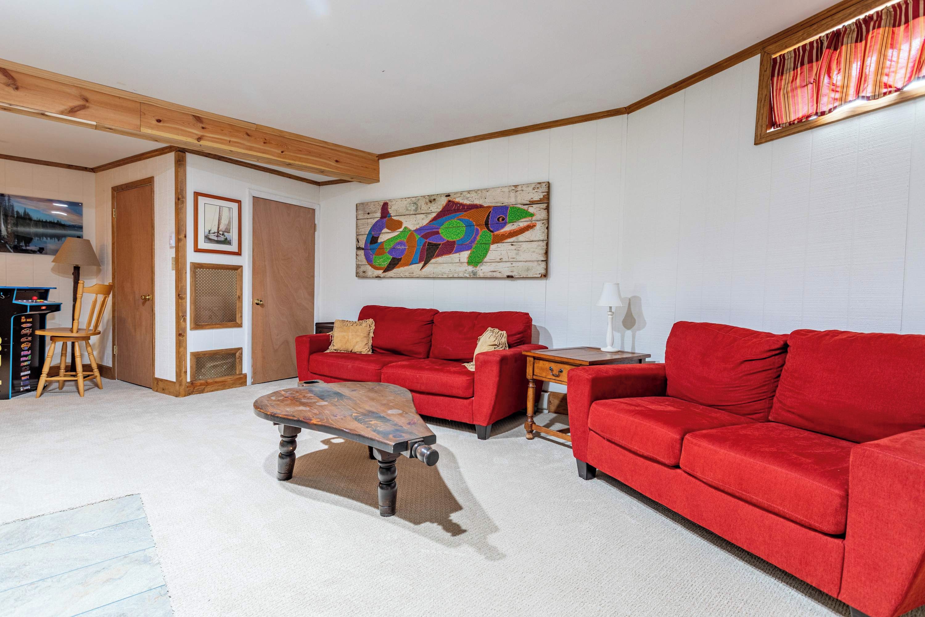 Un salon avec un canapé rouge, une table basse en bois et un tableau abstrait aux couleurs vives accroché au mur.