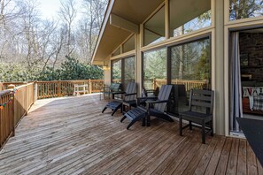 Eine Holzterrasse mit Sitzgelegenheiten und großen Fenstern.
