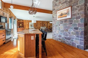 A kitchen with wooden cabinets, a granite countertop, and a stone wall. - Hidden Treasure Chalet Hot Tub | Game Room (Pocono Pines)