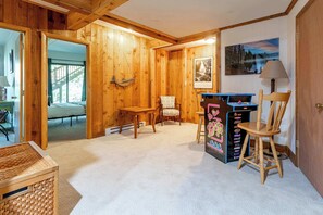 A wooden interior with a bed, a desk, a chair, and a wall-mounted picture. - Hidden Treasure Chalet Hot Tub | Game Room (Pocono Pines)
