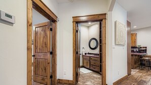 Un pasillo con puertas de madera que dan a un baño y una zona de cocina.