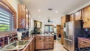 Una cocina con armarios de madera, un refrigerador de acero inoxidable y una isla central con pileta y cajones.