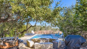 Un área de piscina con sillones de descanso, una fogata y asientos de piedra.