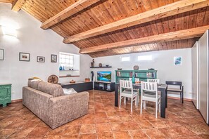 A cozy living room with a sofa, dining table, chairs, and a TV. - Una Mansarda Nell'isola (La Maddalena)