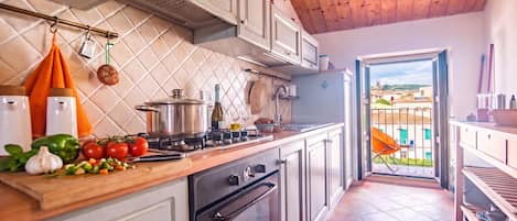 A kitchen with a stove, oven, and various cooking utensils. There is a window with a view of buildings outside.