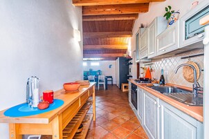 Una cucina con travi in legno, un'area pranzo con sedie e vista su una stanza blu sullo sfondo.