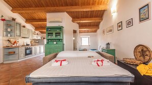 A room with a bed, a green cabinet, and a kitchen area.