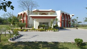 A building with a symmetrical facade, featuring a central entrance flanked by two sets of arches. - Blue Bird Hisar (Hisar)