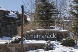A stone sign with the name 'Tamarack' in front of a building with a snow-covered roof.