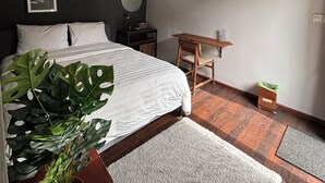 Et moderne soveværelse med seng, sengebord, fjernsyn og en potteplante.