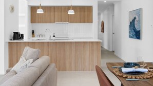 A modern kitchen with wooden cabinets, a white countertop, and pendant lighting. - Secluded 4-Bed Retreat Mins to Beaches & Wineries (Victoria Point)