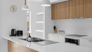 A modern kitchen with white cabinetry, a built-in oven, a sink, and pendant lighting. - Secluded 4-Bed Retreat Mins to Beaches & Wineries (Victoria Point)