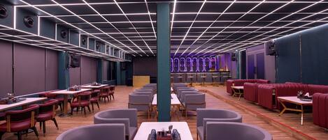 Un restaurante moderno con techo de diseño en cuadrícula, varias zonas de estar con mesas redondas y cabinas, y un pilar central.