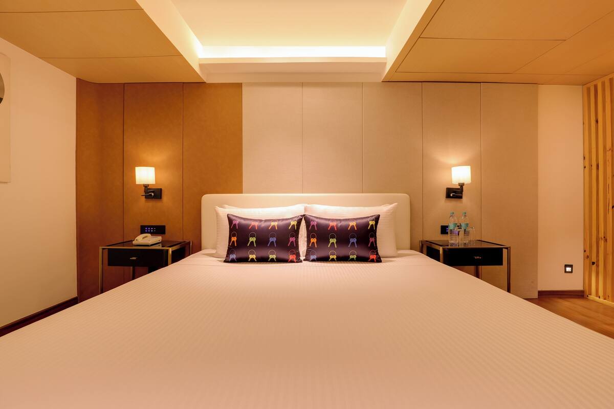 Ein Hotelzimmer mit einem großen Bett, zwei Nachttischen mit Lampen und einer Wand aus Holzpaneelen.