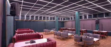 A modern restaurant with red booths, round tables, and a grid-patterned ceiling.