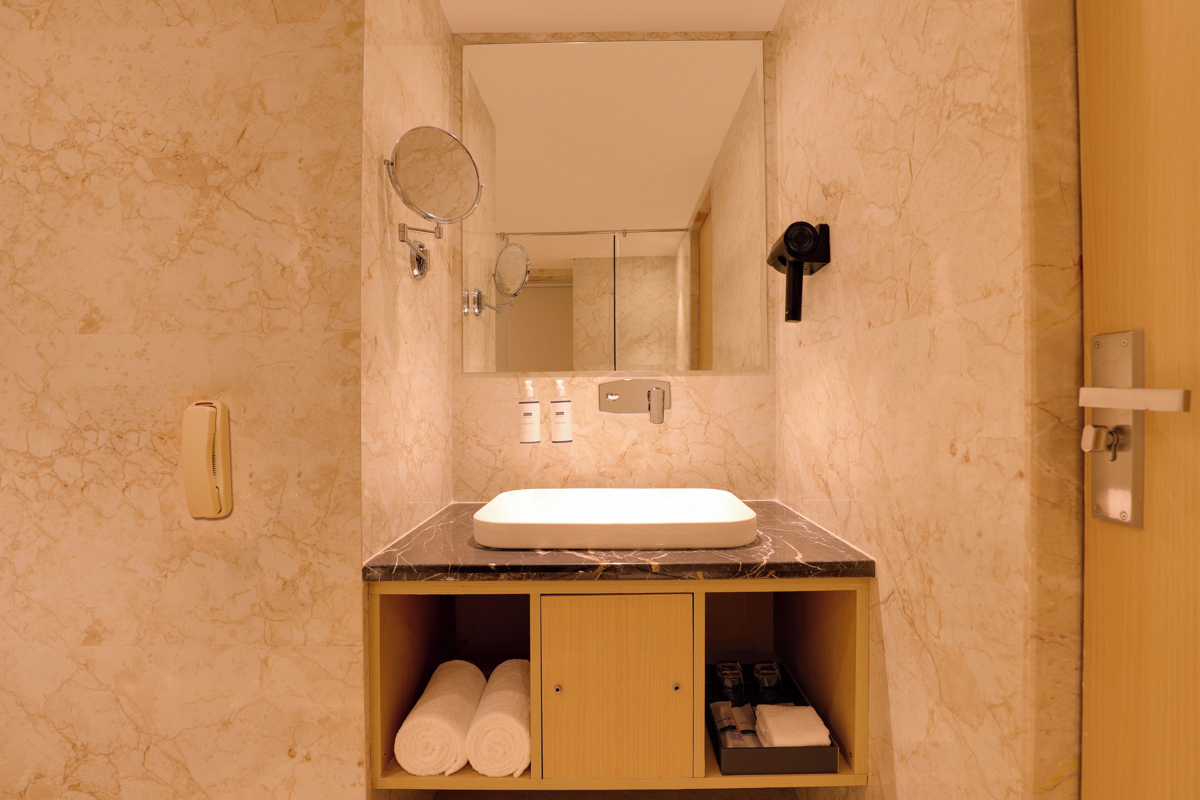 A bathroom with a marble sink, a mirror, a towel rack, and a wooden cabinet.