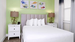 A bedroom with a bed, two nightstands, and three wall-mounted paintings.