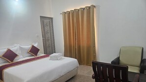 A hotel room with a bed, a chair, a table, and a curtain. - Welcome Inn Express (Bengaluru)