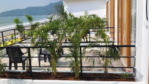 A balcony with a view of the sea, surrounded by potted plants and a wooden fence. - Vivaans Beach Resort (Canacona)