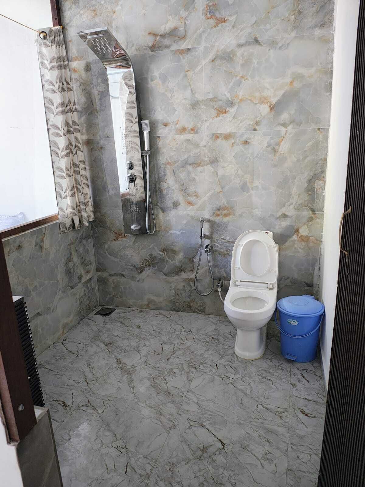 A bathroom with a marble floor, a shower, and a toilet.