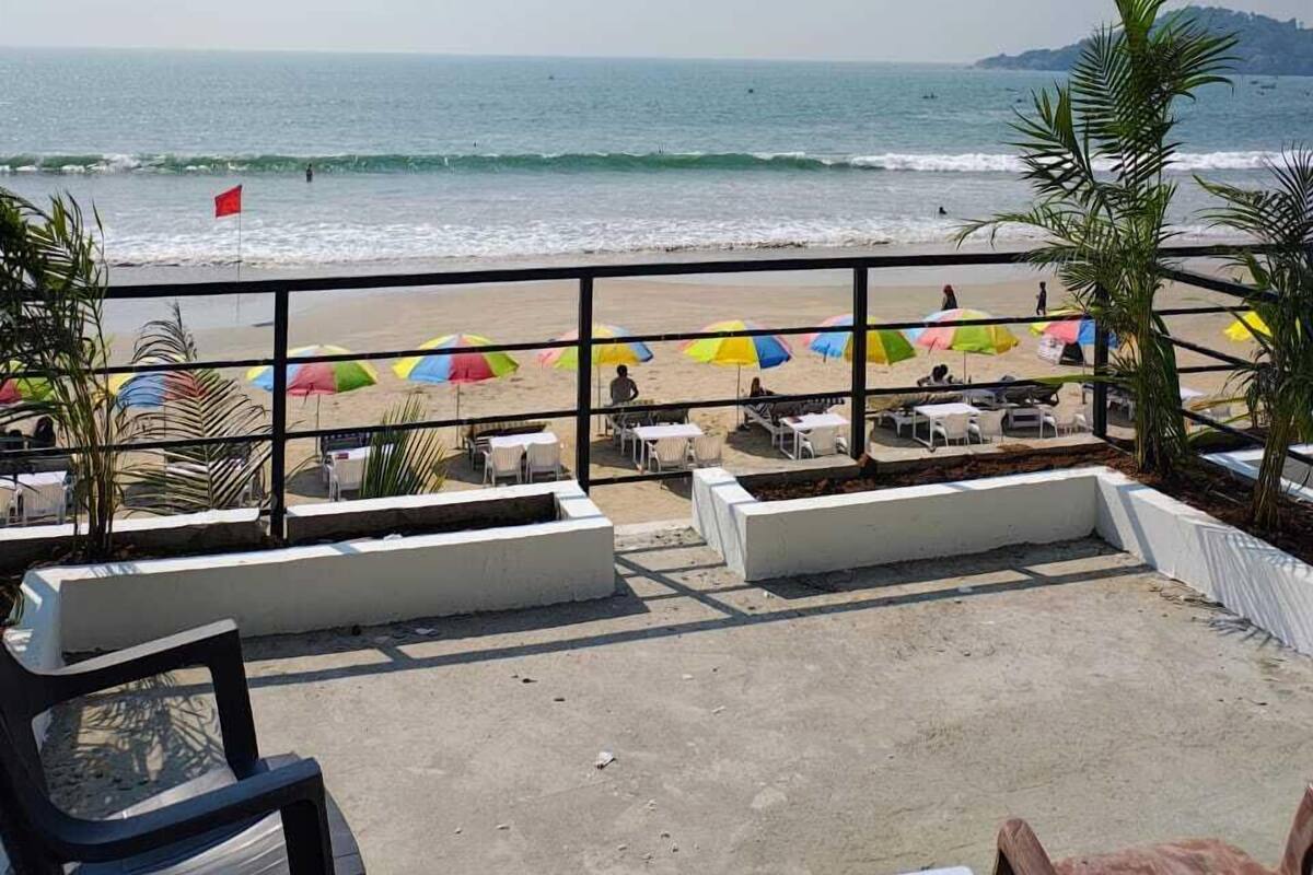 A beachside patio with outdoor seating and umbrellas, overlooking the ocean.